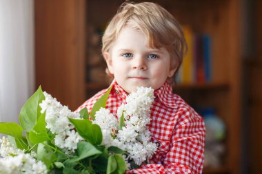 Leylak çiçekli neşeli çocuk. Anneler Günü 'nde gülümseyen küçük çocuk. Aşk ve romantik konsept