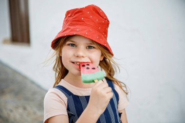 Güzel küçük kız yazları dondurma yer. Karpuzlu kremalı anaokulu çocuğu. Şehir sokaklarında mutlu bir çocuk