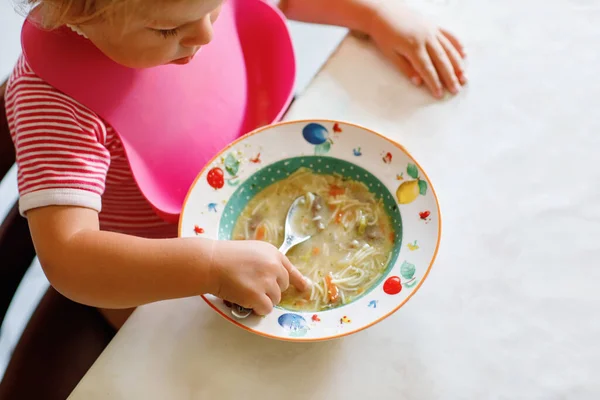 スプーン野菜麺スープから食べる愛らしいベビーガール 健康食品 開発コンセプト かわいい幼い子供は スプーンで座って 一人で食べることを学びます — ストック写真
