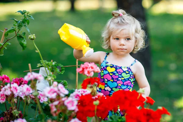 Sød Lille Baby Pige Farverige Badedragt Vanding Planter Blomstrende Blomster - Stock-foto