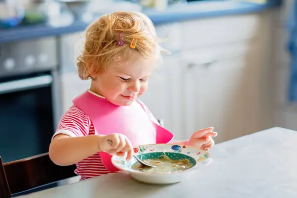 可爱的女婴吃着勺子蔬菜面汤 健康食品 喂养和发展概念 可爱的小孩 带着勺子坐在高椅子上 学习自己吃饭 — 图库照片