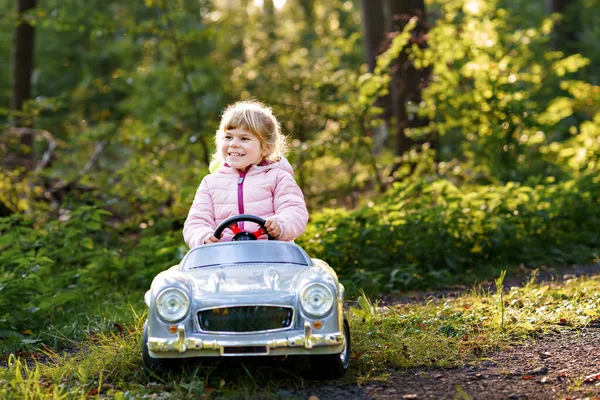 ビンテージのおもちゃの車を運転する小さな幼稚園の少女 アウトドアで遊ぶのが楽しい子供たち 森で暖かい秋の日を楽しんでいるアクティブな幼稚園児 見事な — ストック写真