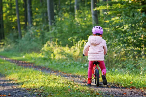 バランスバイクに乗る子供 日当たりの良い森で自転車に乗っている子供たち 暖かい日にグライダーバイクに乗ることを楽しんでいる小さな女の子 安全なヘルメットで走行自転車のバランスをとることを学ぶプリスクーラー スポーツ活動 — ストック写真