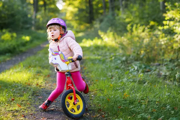 孩子们骑平衡自行车 孩子们骑自行车在阳光灿烂的森林里 小女孩喜欢在暖和的天气里骑滑翔机 学龄前儿童学习如何在安全的头盔中骑自行车保持平衡 体育活动 — 图库照片