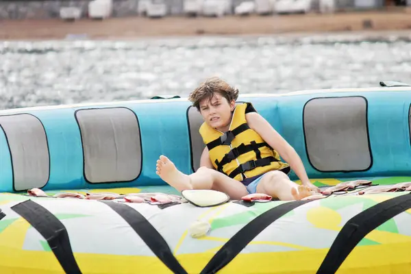 若い少年は 海でボートに引っ張られた膨脹可能なチューブに乗っている間に喜びを露出します 海のアドベンチャーウォーターパークで楽しんでいる幸せな学校の子供 — ストック写真