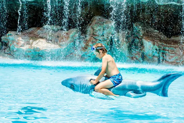 プールでジャンプし ホテルのリゾートで家族の休暇を楽しんで幸せな小さな少年 膨脹可能なサメのおもちゃと水で遊ぶ健康な子供 — ストック写真