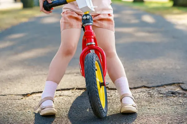 穿着平衡自行车跑步的小女孩的腿被塞住了 快乐的孩子驾驶 骑自行车 户外活动 儿童暑期活动 图库图片
