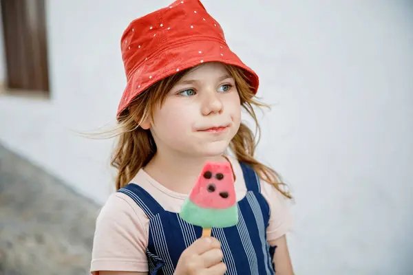 美丽的小女孩夏天吃冰淇淋 有西瓜冰淇淋的学龄前儿童 在城市街道上快乐的孩子 图库图片