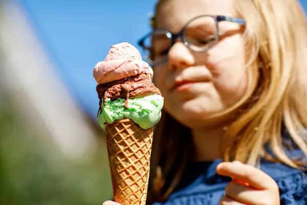 晴れた夏の日にワッフルコーンでカラフルなアイスクリームを食べる幸せな就学前の女の子 小さな幼児はアイスクリームデザートを食べます 暑い夏の日に甘い食べ物 明るい光 カラフルなアイスクリーム ストック写真