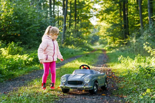 幼儿园的小女孩开着老式的大玩具车 快乐的孩子在外面玩得很开心 活跃的学龄前儿童在森林里享受着温暖的秋天 笑得惊心动魄 — 图库照片