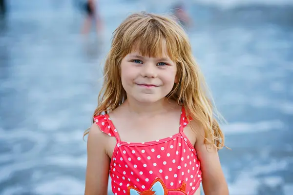 快乐的孩子 的肖像 穿着泳衣的幼稚园女孩在异国热带海滩度假期间在波浪中奔跑和跳跃 海洋海岸的家庭旅程 图库图片