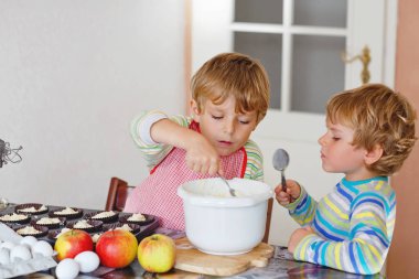 İki komik kardeş ev mutfağında elmalı pasta pişiriyor. Sağlıklı çocuklar mikser, yumurta ve meyvelerle eğleniyor. Çocuklar içeride hamur tadıyor..