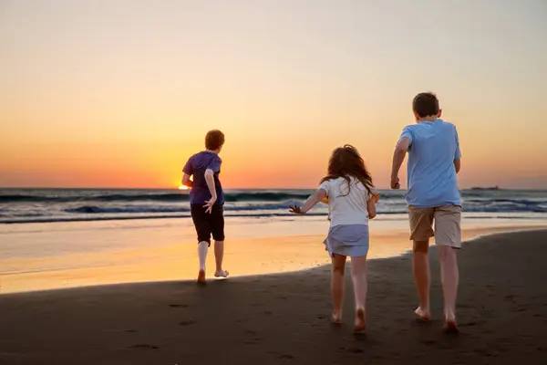 Tři Dětské Siluety Běžící Skákající Pláži Při Západu Slunce Šťastná — Stock fotografie