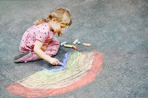学龄前小女孩在后院的地上用彩色粉笔画彩虹 积极快乐的幼儿绘画和创作图片 夏季有创意的户外活动 — 图库照片