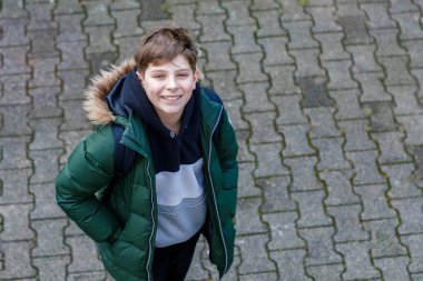 Sırt çantalı, okula giderken ya da okula giderken gülümseyen zeki öğrencinin yakın plan portresi. Sokaktaki mutlu genç çocuk. Ergen kameraya bakıyor. Eğitim kavramı.