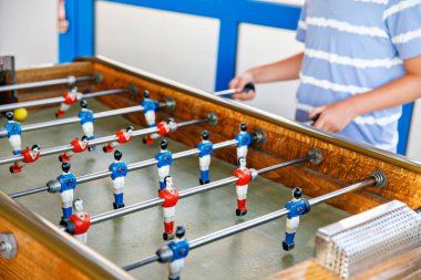 Masa futbolu oynayan çocuğun yakın çekimi. Mutlu heyecanlı çocuk aile oyunlarıyla eğleniyor kardeşleriyle ya da arkadaşlarıyla. Pozitif çocuk.