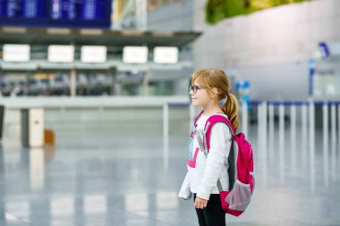 Havalimanı Terminali 'nde gözlüklü küçük anaokulu kızı. Mutlu Çocuk Uçakla Tatile Çıkıyor. Çantalı Gülümseyen Çocuk