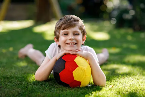 快乐活泼的孩子踢足球与球在德国国旗颜色 健康的孩子玩足球游戏和户外活动的乐趣 免版税图库照片