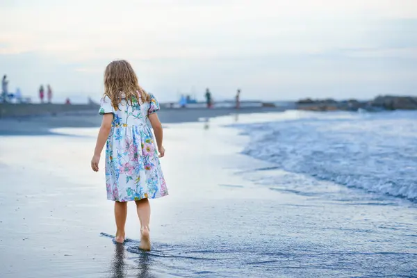在日落前的热带异国海滩度假期间 快乐的孩子 穿着长袍的小女孩在波浪中奔跑跳跃着 海洋海岸的家庭旅程 免版税图库图片