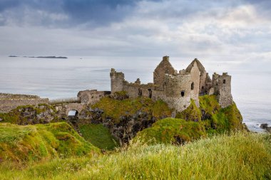 Dunluce Şatosu 'nun kalıntıları, Antrim, Kuzey İrlanda, güneşli bir günde yarı bulutlu gökyüzü. Vahşi Atlantik Yolu yakınlarındaki eski İrlanda kalesi