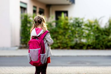 Anaokuluna giden tatlı küçük bir kız. Sağlıklı bir çocuk anaokuluna ve anaokuluna doğru yürüyor. Şehir caddesinde, açık havada sırt çantalı mutlu bir çocuk.