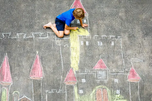 アスファルトの上の騎士城やカラフルなチョークで要塞を描く少し活発な子供少年 チョーク絵の作成を楽しんで幸せな幼児 子供と夏の子供のための創造的なレジャー ストックフォト