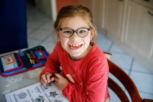 一个快乐的小女孩在家里做作业的画像 小学学习写作和学习 微笑着给孩子写信 学习写字 图库图片