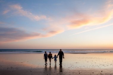 Gün batımında üç çocuk ve babanın resimli mutlu çocukları ve babaları sahilde. Mutlu bir aile, iki okul çocuğu ve küçük bir anaokulu kızı. Kardeşler birlikte eğleniyor. Bağlanma.