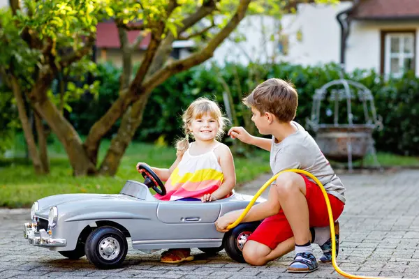 Zwei Glückliche Kinder Spielen Mit Einem Großen Alten Spielzeugauto Sommergarten lizenzfreie Stockfotos