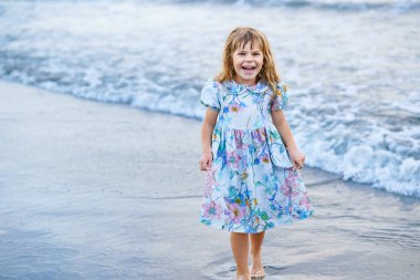Mutlu Çocuk, Güneş batana kadar Tropik Plajda Yaz Tatili sırasında Koşan ve Dalgalarda Atlayan Küçük Okul Öncesi Kız. Okyanus Kıyısındaki Aile Seyahati