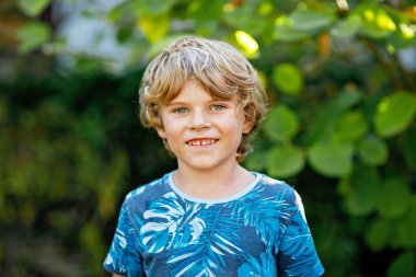 Açık havada çekilen mutlu okul çocuğu portresi. Sarışın, gülümseyen yakışıklı çocuk, açık havada..