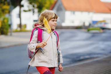 Okuldaki ilk gününde tatlı küçük bir anaokulu kızı. Sağlıklı, mutlu bir çocuk anaokuluna gidiyor. Sırt çantalı çocuk şehir sokaklarında kreşe gidiyor..