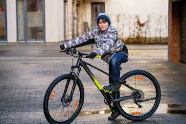 Okula bisikletle giden yakışıklı bir çocuk. Ergen bisikleti. Liseye gitmek için güvenli bir yol. Bisikletli mutlu çocuk. Genç bir öğrenci için sağlıklı açık hava aktivitesi.