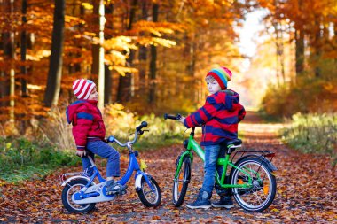 İki küçük çocuk çocuklar, Bisikletleri ile sonbahar ormandaki en iyi arkadaş. Etkin kardeş, çocuk bisiklet ile. Renkli moda erkek birlikte eğleniyor, gülen ve gülümseyen güneşli günde giyim sonbahar