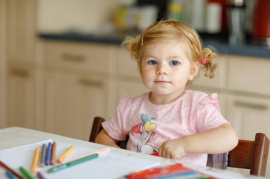 Kalemle resim yapmayı öğrenen sevimli bir bebek. Küçük çocuk renkli keçeli kalemlerle evde resim çiziyor. Evde ya da çocuk odasında renkler deneyen sağlıklı, mutlu bir kız.