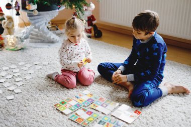 İki küçük çocuk, küçük tatlı kız ve okul çocuğu süslü Noel ağacında kağıt oynuyorlar. Mutlu sağlıklı kardeşler, erkek ve kız kardeşler birlikte eğleniyor. Aile Xmas kutlaması