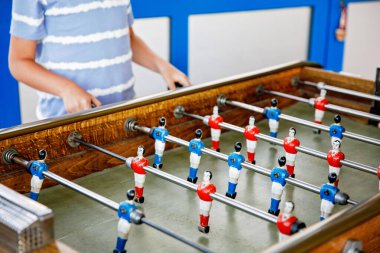 Masa futbolu oynayan çocuğun yakın çekimi. Mutlu heyecanlı çocuk aile oyunlarıyla eğleniyor kardeşleriyle ya da arkadaşlarıyla. Pozitif çocuk.