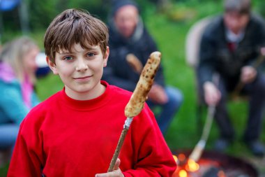 Genç çocuk yaz kampında kızarmış ekmek çubuğunu ateşe veriyor. Mutlu çocuk tatillerini spor kampında geçiriyor.
