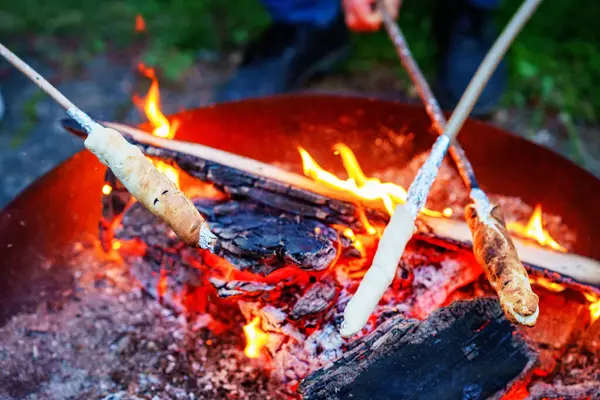 stock image Stick bread twisted on skewer or stick, roasted on flame of fire. Popular party and camp barbecue food in Germany called Stockbrot. Fun for children. Healthy snack