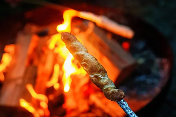 stock image Stick bread twisted on skewer or stick, roasted on flame of fire. Popular party and camp barbecue food in Germany called Stockbrot. Fun for children. Healthy snack