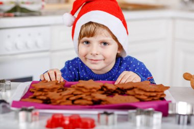 Kreş çocuğu zencefilli kurabiye pişiriyor. Xmas süveter giyen mutlu, yeni yürümeye başlayan çocuk. Mutfak Noel için dekore edildi. Noel aile aktivitesi.