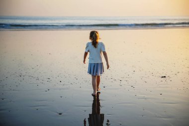 Gün batımında sahilde küçük mutlu bir kız. Uzun sarı saçlı anaokulu çocuğu İspanya 'da aile tatillerinde eğleniyor, Costa del Sol.