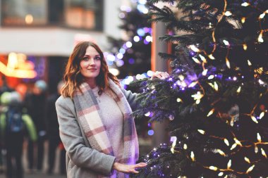 Güzel genç bir kadın, şiddetli kar yağışında geleneksel Noel pazarında eğleniyor. Mutlu kız Almanya 'da geleneksel aile pazarının tadını çıkarıyor. Aydınlatılmış Xmas ağacının yanında duran kadın