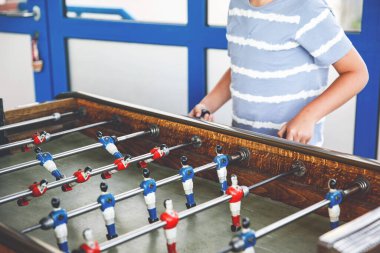 Masa futbolu oynayan çocuğun yakın çekimi. Mutlu heyecanlı çocuk aile oyunlarıyla eğleniyor kardeşleriyle ya da arkadaşlarıyla. Pozitif çocuk.