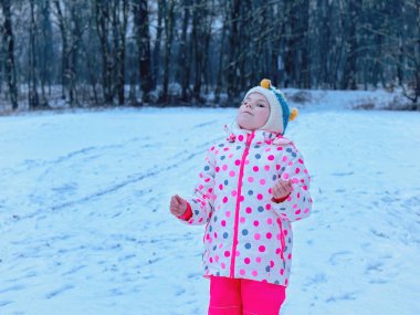 Güzel Kış Parkı 'nda Eğlenen Komik Küçük Kız. Karla oynayan mutlu okul çocuğu, kar ve kış aktiviteleriyle ilgili mutluluk.