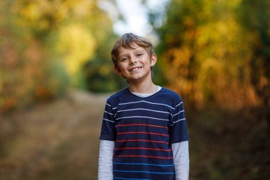 Ormandaki küçük havalı çocuğun portresi. Mutlu sağlıklı çocuk sıcak güneşli bir sonbaharda eğleniyor. Aile, doğa, aşk ve aktif eğlence.