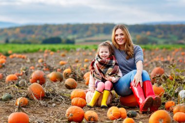 Mutlu kadın ve küçük kız, balkabağı tarlasında çiftçilik yapan kız. Çocuklu geleneksel aile festivali, Şükran Günü ve Cadılar Bayramı konsepti. Sonbahar renkleri