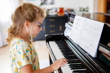 Küçük liseli kız piyano çalmayı öğreniyor. Evde ya da müzik okulunda müzik enstrümanı çalan heyecanlı bir çocuk..
