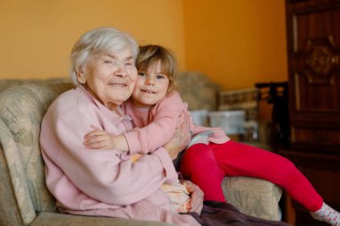 Küçük güzel bir kız ve büyük büyükannesi evde birbirlerine sarılıyorlar. Tatlı çocuk ve son sınıf öğrencisi birlikte eğleniyorlar. Mutlu aile içeride..