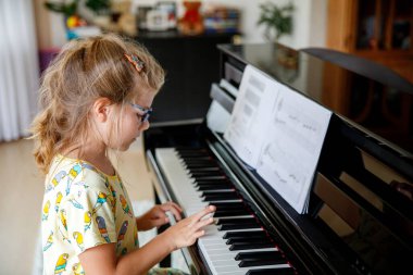 Küçük liseli kız piyano çalmayı öğreniyor. Evde ya da müzik okulunda müzik enstrümanı çalan heyecanlı bir çocuk.